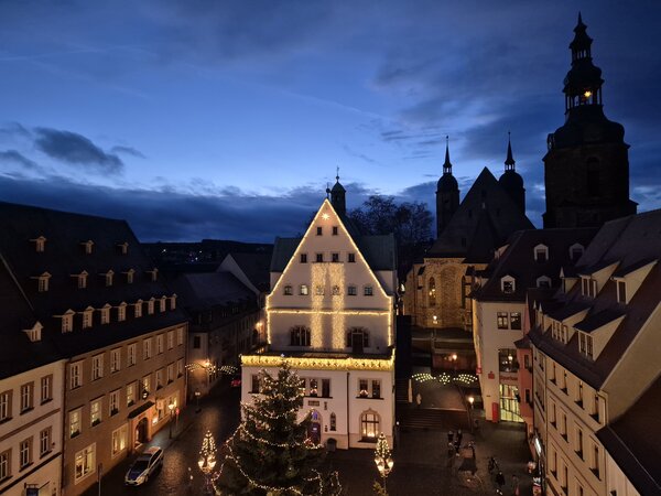 Der beleuchtete Weihnachtsmarkt von oben mit Weihnachtsbaum vorm Rathaus und Marktkirche im Hintergrund