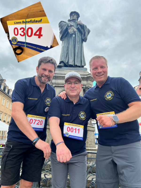 Bild vergr&ouml;&szlig;ern: Das Bild zeigt drei M&auml;nner, die nebeneinander stehen und in die Kamera l&auml;cheln. Sie tragen alle dunkelblaue Shirts mit dem Logo des Lions Club und Startnummern. Im Hintergrund ist die Statue von Martin Luther zu sehen und dar&uuml;ber ein bew&ouml;lkter Himmel. Links oben im Bild ist ein eingeschnittenes Foto einer Startnummer mit der Aufschrift "Lions Benefizlauf" und der Nummer 0304 zu sehen